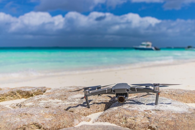 Drone landed on rocks surface next to seashore. Blurred tropical beach shore, coastline landscape