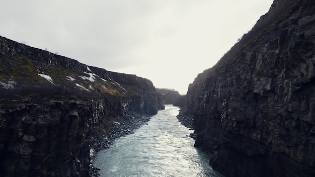 Drone-opname van de IJslandse gullfoss-cascade, majestueuze waterstroom die tussen rotsachtige heuvels en kliffen stroomt. Prachtige waterval in ijsland loopt van bergen af, winterlandschap. Slow motion.