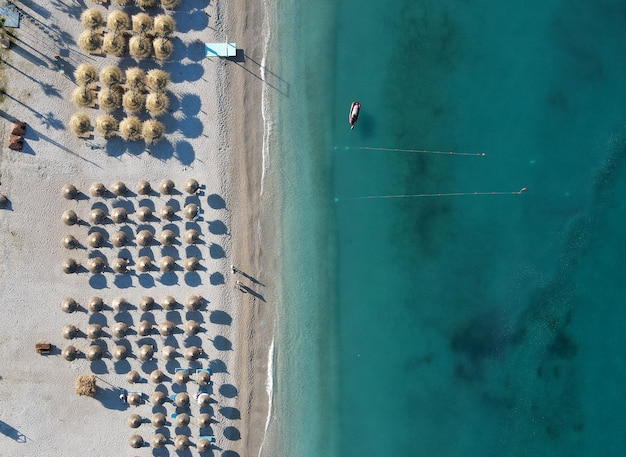 アルバニア ボルシチのイオニア海沿岸でパラソルを持った夏のビーチ リゾートのドローン写真