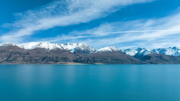 Drone photograph of the shore of lake pukaki and the snow capped southern alps pesaks in the backg