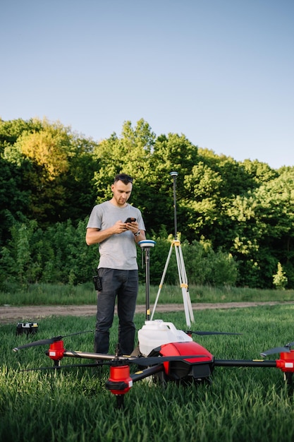 A drone pilot configuring his drone in a field with and irrigation system before flying