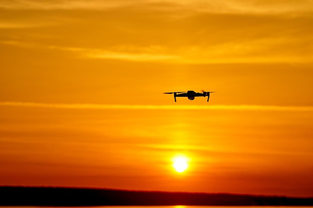 Drone quadcopter met digitale camera die bij zonsondergang vliegt