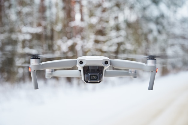 Drone quadcopter with camera flying in the winter forest