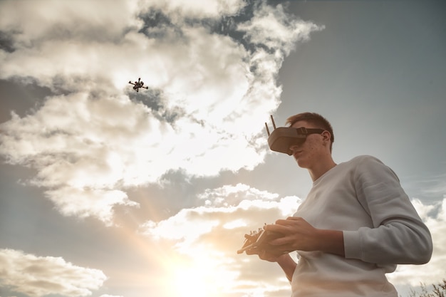 무인 항공기 비행, 남자는 야외에서 디지털 안경 손에서 작동합니다. 작은 비행 카메라와 함께 비행 하는 공중 헬리콥터를 출시 하는 젊은 남자. 우리 생활에서 현대 기술의 개념입니다. 복사 공간