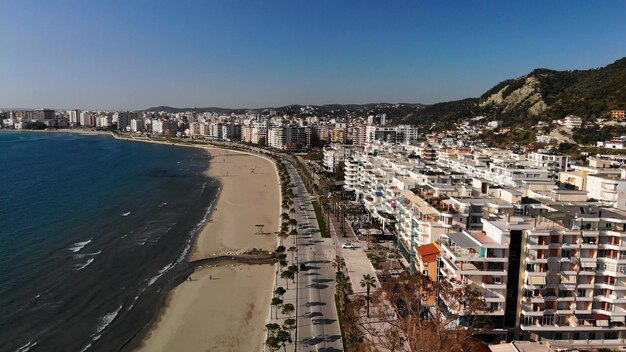 Drone shot of the beach in a bright day with trees and blue water