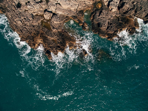 A drone shot of a beautiful rocky beach with clear turquoise sea water