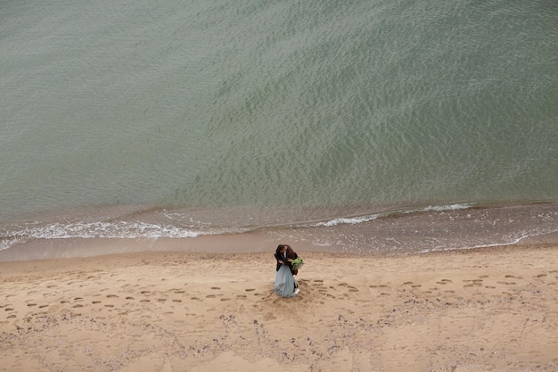 Drone shot from above of two lovers walking on the beach of sea