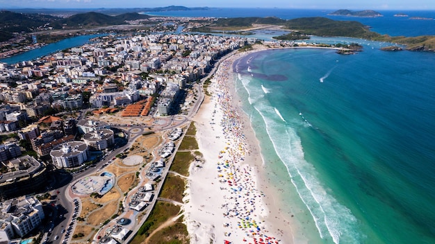 Foto drone-uitzicht op het strand met groene en blauwe zee wit zand met parasols in de stad cabo frio
