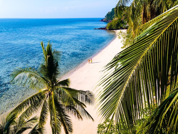 Drone view at the beach of koh kradan island in thailand couple men and woman walking on the beach