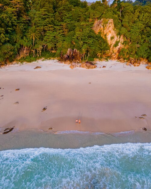 Drone view at the beach of koh kradan island in thailand couple men and woman walking on the beach