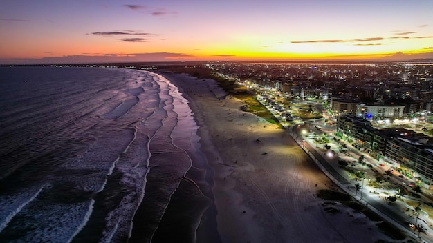 Foto vista drone su una spiaggia di notte o al tramonto con le luci della città sulla città di cabo frio in brasile