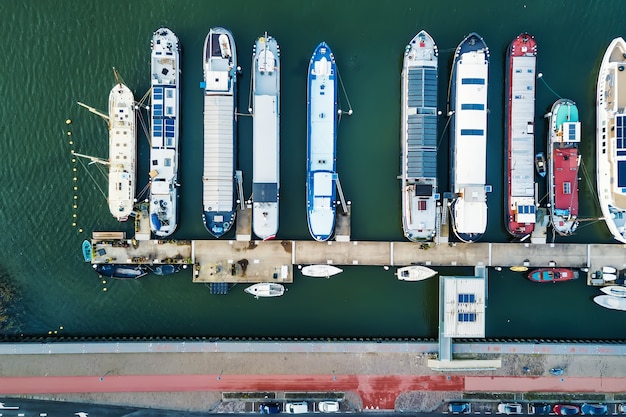 Вид с дрона на современные баржи и лодки, плавающие в морской воде возле набережной в городе