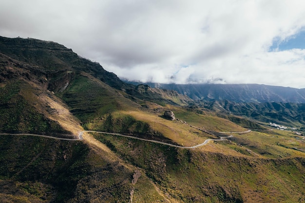 カラフルな山の風景の真ん中にある荒れ果てた道路のドローンビュー