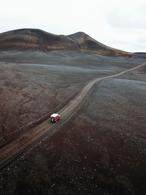 未舗装の道路を運転するスズキジムニーのドローンビュー