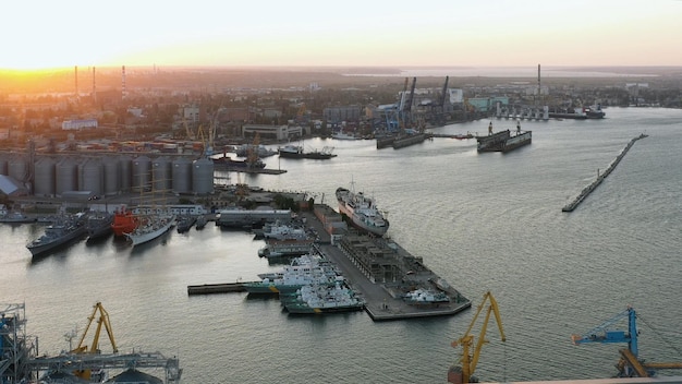 Drone view of urban sea port with cargo ships and grain terminals evening sunset light