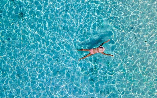 Drone view at a woman swimming in the blue turqouse colored ocean of koh kradan island in thailand