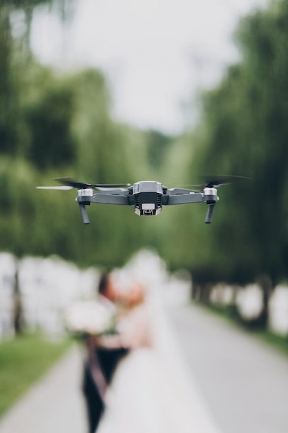 Drone vliegen in groen park Drone foto's en beelden van trouwdag concept Zwarte drone op achtergrond van wazig bruidspaar in groen park