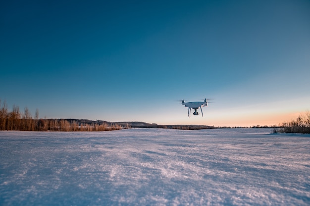 Drone vliegt boven veld bedekt met sneeuw op zonnige winterdag