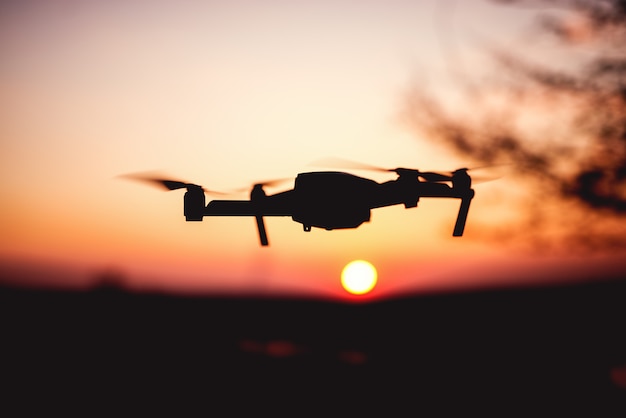 Drone vliegt in de zonsondergang. Silhouet van drone tegen kleurrijke hemel.