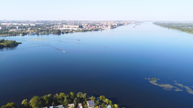 Drone vliegt over een golvende rivier van blauwe kleur, omringd door een lokaal dorp