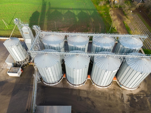 Drone-vlucht over een groot agro-industrieel complex en vaten graansilo's in de agro-fabriek voor het verwerken, drogen, reinigen en opslaan van landbouwproducten, meel, granen