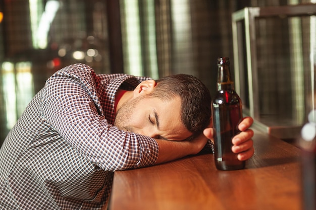 Foto dronken man slapen op de bar met glas op bier