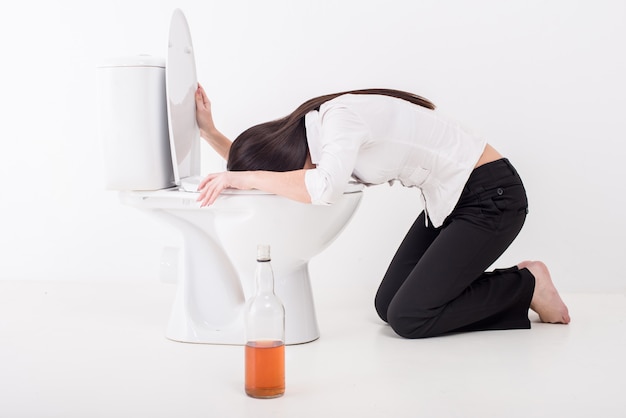 Foto dronken vrouw die op een toiletkom braken.