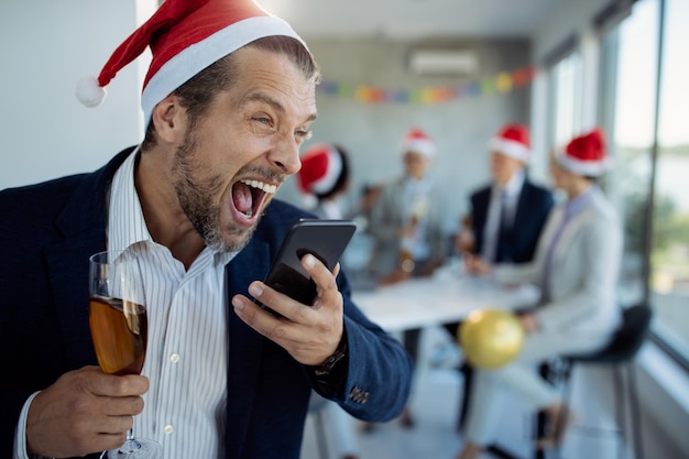 Dronken zakenman schreeuwt op mobiele telefoon terwijl hij telefoneert tijdens kerstfeest op kantoor