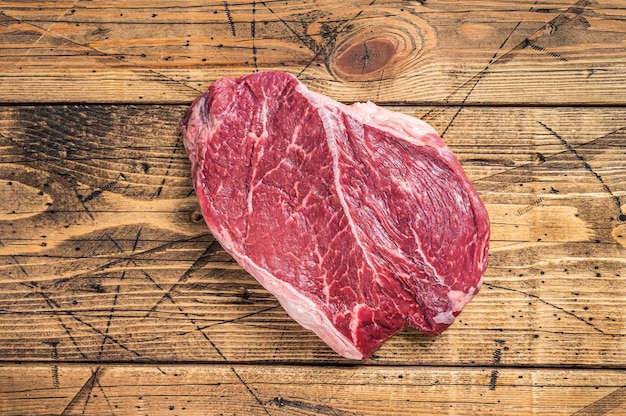 Droog gerijpt rauw rundvlees ronde steak gesneden op een slager tafel. houten achtergrond. Bovenaanzicht.