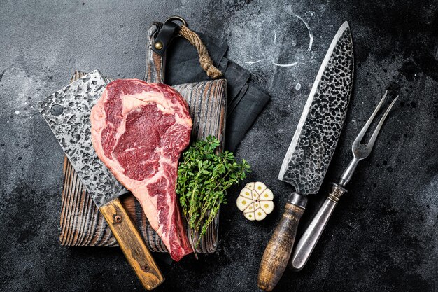 Droog gerijpt Tomahawk rib eye steak rauw rundvlees op slagerstafel Zwarte achtergrond Bovenaanzicht