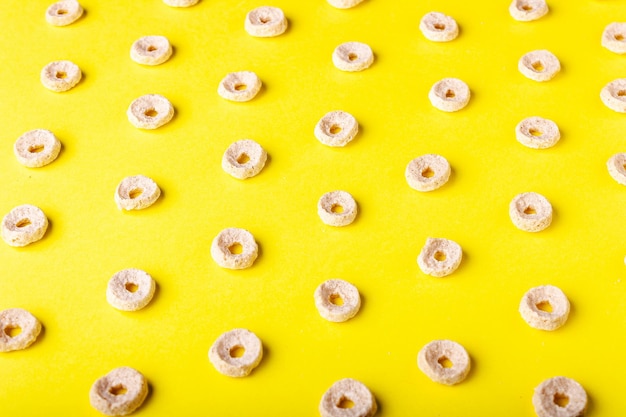 Droog ontbijt in de vorm van ringen op een geel achtergrondpatroon