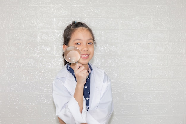 Droom carrières concept, portret van gelukkig kind in wetenschap jas met vergrootglas op onscherpe achtergrond