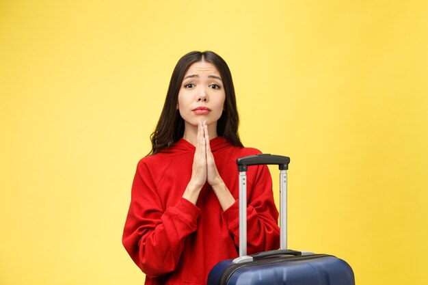 Droom over reizen en vakantie. Studio portret van opgewonden vrij jonge vrouw met biddende handen.