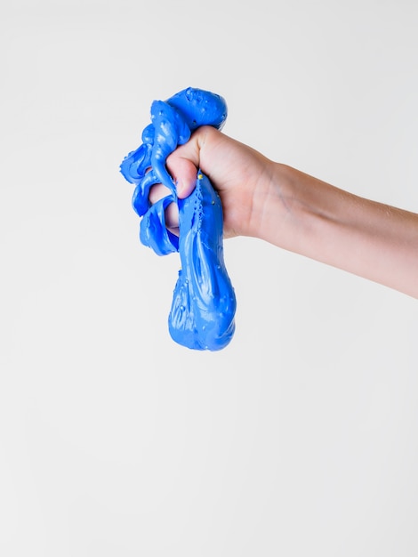 A drop of blue slime flows out of the child's hand isolated on a white background.