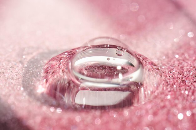 A drop of cosmetic gel on a pink shining background