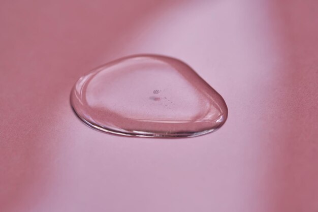 A drop of cosmetics or perfume on a pink background