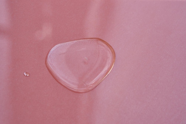 A drop of cosmetics or perfume on a pink background