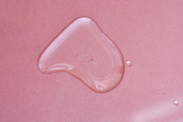 A drop of cosmetics or perfume on a pink background