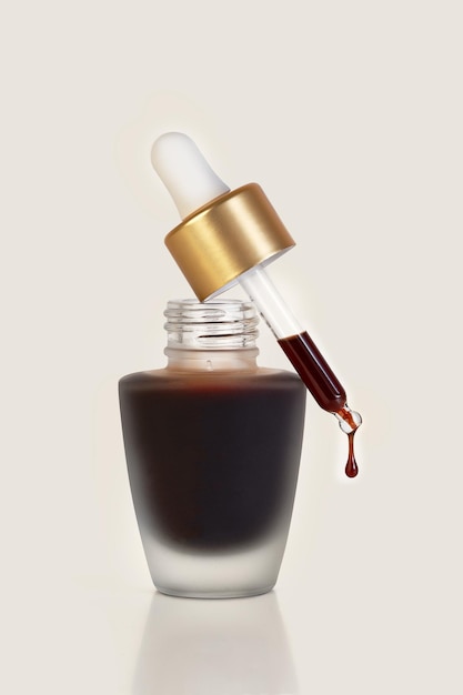 Photo a drop of face selftanning concentrate drips from a pipette into a bottle