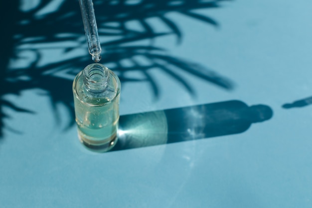 drop falls from a pipette into a glass bottle with cosmetic oil or serum