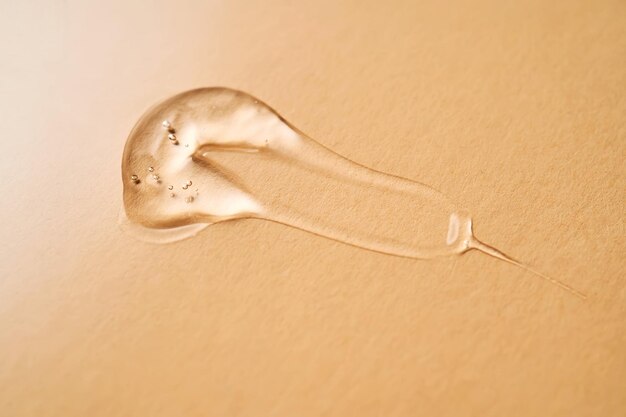 A drop of transparent cosmetic gel on a beige background