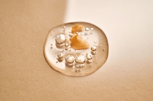 A drop of transparent cosmetic gel on a beige background