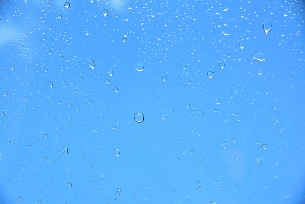 Goccia d'acqua su vetro su sfondo blu cielo