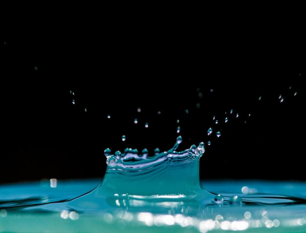 droplets falling on rippled water against black background