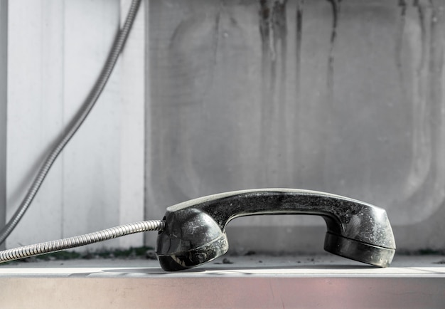Фото Уронили телефонную трубку-автомат, лежащую на поверхности металлической будки, покрытой пылью. смерть общественной кабельной телефонной связи