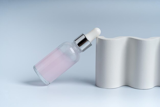 A dropper bottle for face care on a white concrete podium presentation of product marketing