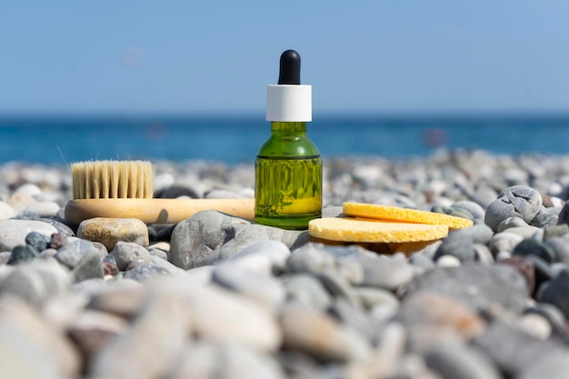 A dropper bottle of face serum or natural oil standing on the stones on the beach