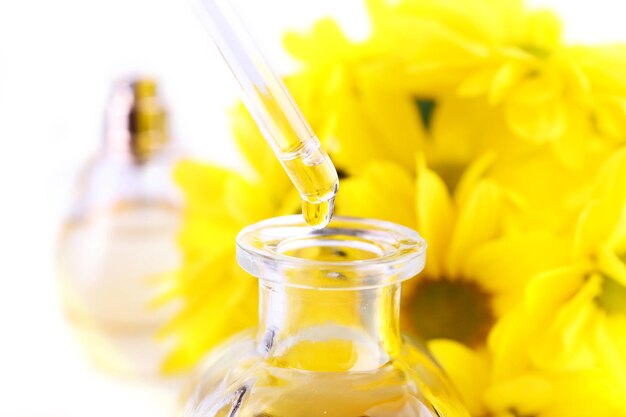 Photo dropper bottle of perfume with yellow chamomile on white background