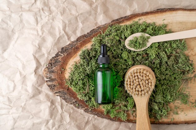 A dropper bottle of serum or oil with vitamin C and a face brush lying on a wooden tray