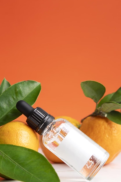 Dropper bottle with white label mockup Moisturizing aromatherapy detox treatment antistress effect Fresh fruit green leaves orange background